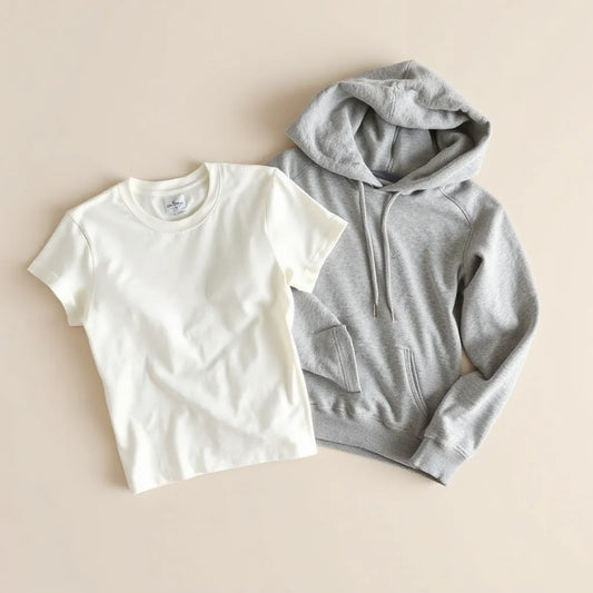 Neatly folded 100% cotton apparel including a T-shirt and hoodie with visible soft fabric texture