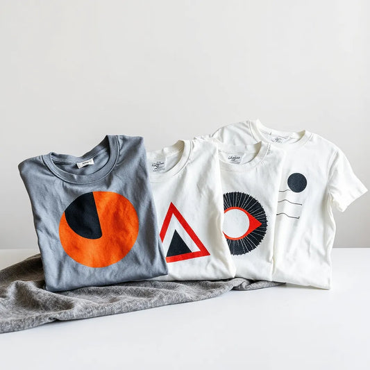 Folded graphic t-shirts featuring bold geometric and abstract designs on a clean studio table
